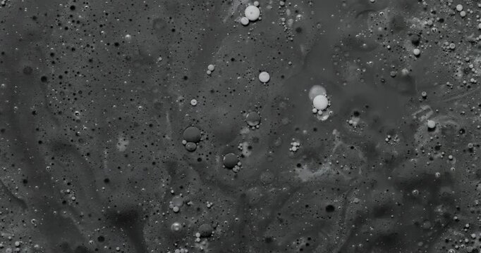 Black bubbly liquid. Close-up of dark viscous surface with foam and bubbles. 