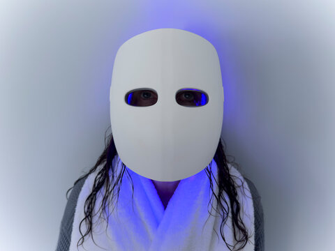Studio shot of woman using LED light therapy mask
