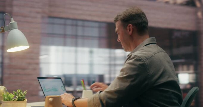 360 Degree. Caucasian Man Using Laptop Computer While Working in Office, Analyzing Business Data, Financial Charts and Statistical Graphs on Screen. Orbital Cinematic Arc Tracking Shot.