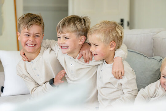 Young boys sitting on the couch with arms over each others shoulder