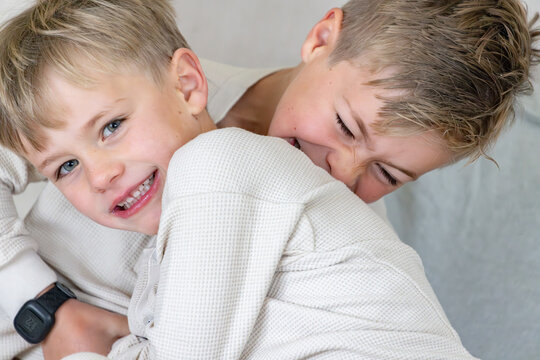 Two young boys playfully wrestling on the couch