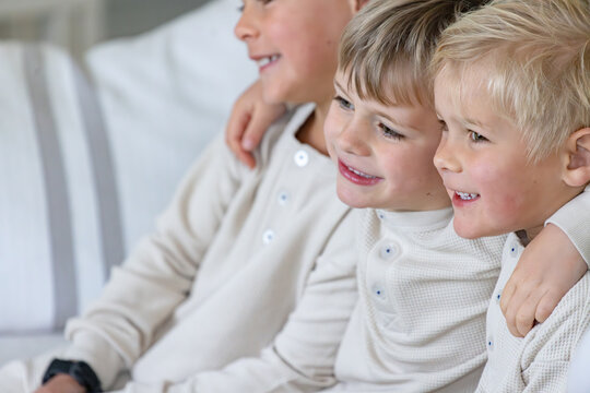 Young boys sitting on the couch with arms over each others shoulder
