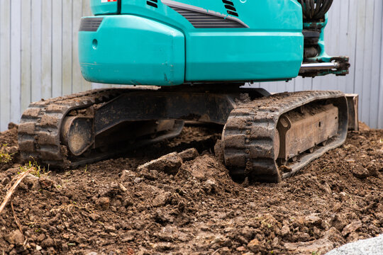 Excavator positioned on a mound of soil and rocks