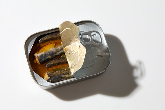 Open tin of sardines on white background