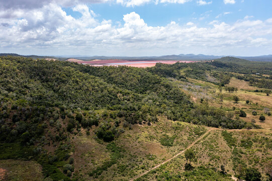 Aerial view of hill with red mud dam in background