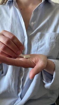 Woman keeping in hand two big white pills close up. Taking daily dose of vitamins and supplements, home treatment, woman's health, healthcare and medicine, biohacking
