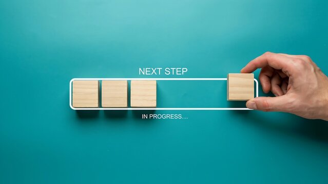 Hand placing a wooden block into a progress bar to symbolize moving forward and successfully completing project management milestones and growth