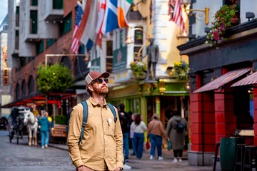 A man stands in the iconic Temple Bar district of Dublin, looking up amidst the characteristic flags and bustling atmosphere of the famous street. © Agnieszka Gaul