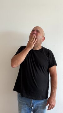 Hombre latino de 50 a&ntilde;os bostezando con mano en boca