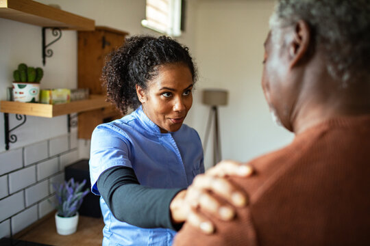 Female caregiver comforting senior man at home