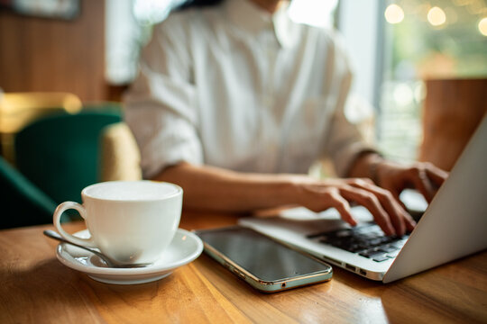 Person working on laptop in cafe with coffee