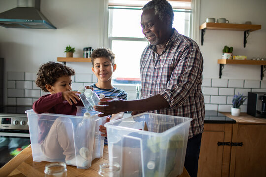 Grandfather and children sorting recycling in kitchen