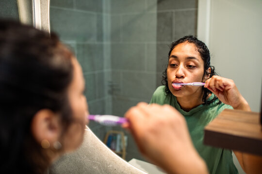 Young woman brushing teeth in home bathroom