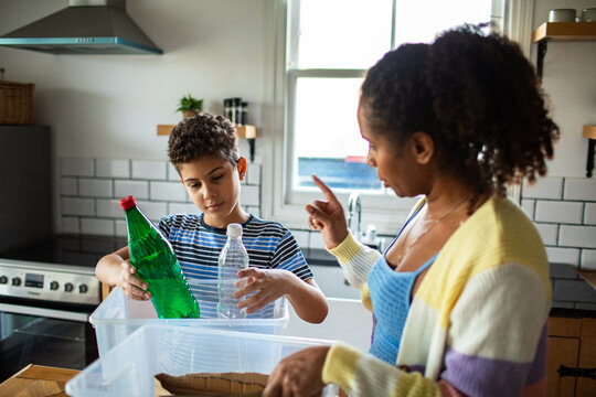 Mother and son recycling plastic bottles in home kitchen