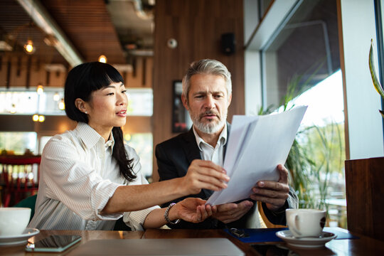 Two business colleagues reviewing documents in a cafe