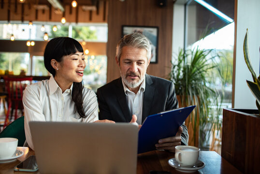 Business colleagues reviewing report over coffee in cafe