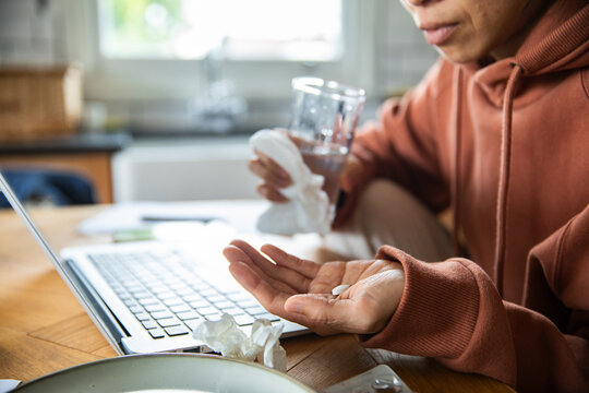 Sick adult taking medicine while working from home