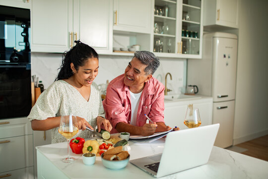 Smiling couple cooking dinner together at home kitchen