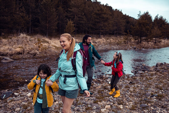 Parents and children hiking along forest riverbank