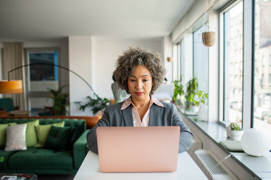 Mature businesswoman working on laptop in bright modern office