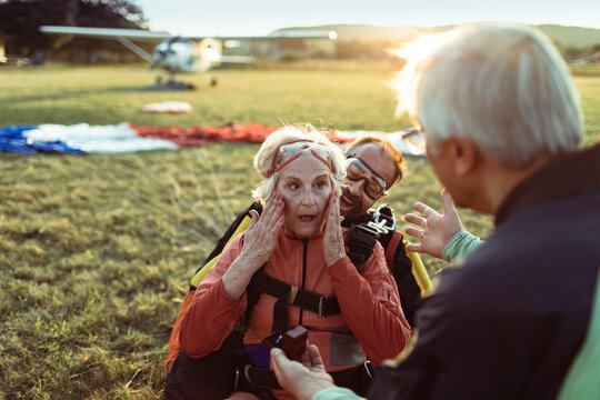 Senior woman surprised by engagement proposal after tandem skydiving landing at airfield