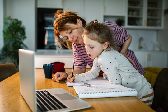 Mother helping daughter with homework at kitchen table