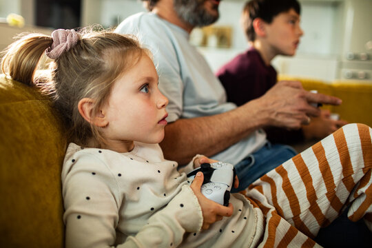 Family playing video games together on living room couch at home