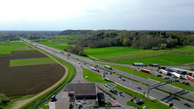 Aerial drone footage of E314 highway with Esso gas station and truck rest area in Rotselaar, Belgium surrounded by green farmland