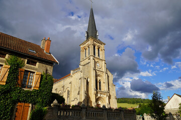 Obraz premium St Pierre church, Église Saint-Pierre in Pouilly-en-Auxois (1868) with dark rain clouds and blue sky. June, France, Burgundy.