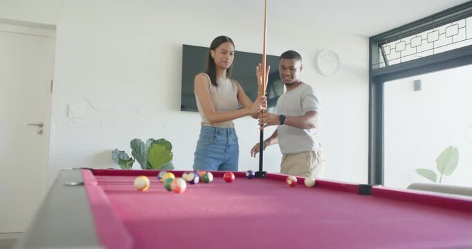 Couple practicing at home by red pool table while man holding cue upright teaching grip