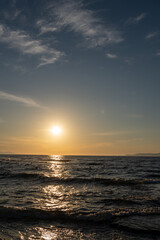 Fototapeta premium Vertical shot of golden sunset reflecting on dark sea water