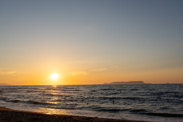 Obraz premium Golden sunset over ocean with distant island and sun path
