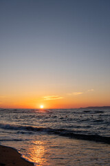 Obraz premium Vertical shot of golden sun touching the sea horizon at sunset
