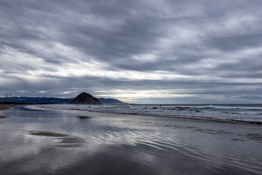 Storm clouds above beach with Morro Rock in distance