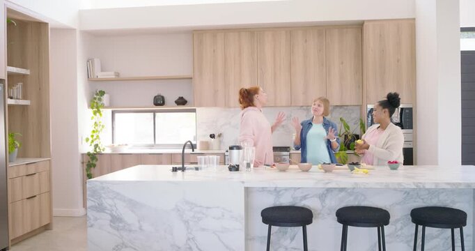 Diverse female friends saying hellos, chatting, peeling bananas and prepping bowls at marble island