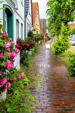 Narrow historic lane in Arnis with roses, flowers, brick pavement and traditional homes in the smallest town of Germany.