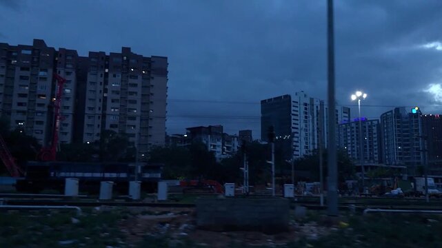 Dynamic evening cityscape of Bengaluru, India, showcasing urban residential high-rises and ongoing development under a dramatic, cloudy sky.