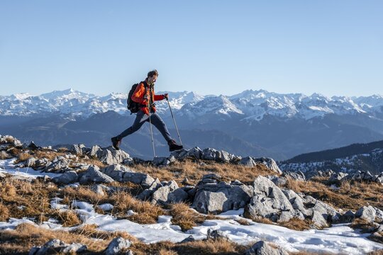 Mountaineer taking a big step, in front of mountain panorama, hiking trail at Guffertstein, in the background main ridge of the Alps with Gro&szlig;venediger, in autumn, Brandenberg Alps, Tyrol, Austria