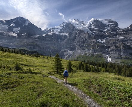 Two (hikers) on a hiking trail, in front of the Eiger north face, behind mountains and mountain tops, steep face and mountains, Jungfrau region, Lauterbrunnen, Bernese Alps, Switzerland