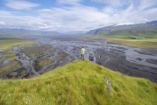 Hiker, young man on a hill, view over alluvial land, meandering river, D&iacute;monarhellir, Su&eth;urland, Iceland