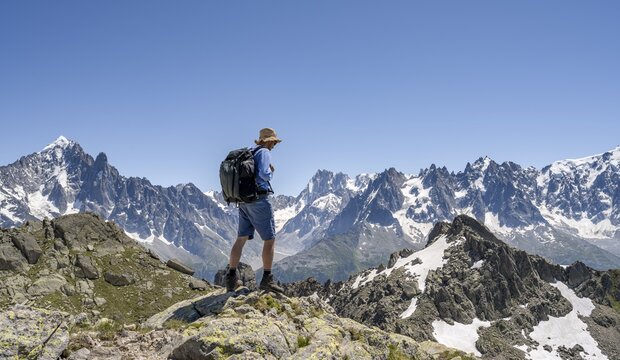 Mountaineer on a rock, mountain landscape with mountain peaks Aiguille Verte and Grandes Jorasses, Mont Blanc massif, Aiguilles Rouges, Chamonix-Mont-Blanc, Haute-Savoie, France