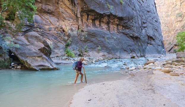 Hiker crossing river, Zion Narrows, narrow of the Virgin River, steep faces of Zion Canyon, Zion National Park, Utah, USA