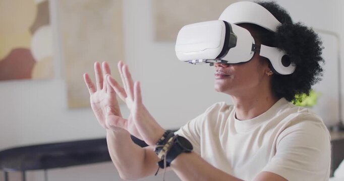 Adult male wearing white VR headset, tshirt using virtual objects after app starts in living room