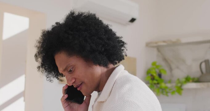 African American man holding smartphone during call, sorting papers to reference files on table