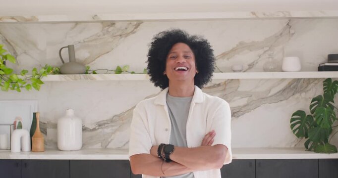 African American man arms crossed camera tightening smile widening laughing by marble backsplash