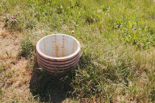 Circular Concrete Well Ring on Grassy Hill with Wildflowers Under Sunny Daylight for Rural Construction and Infrastructure Concepts
