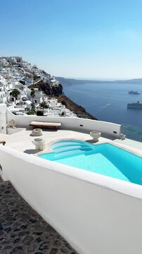 White architecture in Santorini island, Greece. Luxury swimming pool with blue water. Blue sea and the blue sky at sunny day. Travel and summer vacation concept. Vertical video

