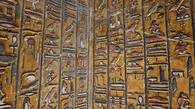 Close-up of ancient Egyptian relief carving inside KV17 tomb of Seti I, Valley of the Kings, Luxor, Egypt, showing a deity figure with black hair and deteriorating pigment.