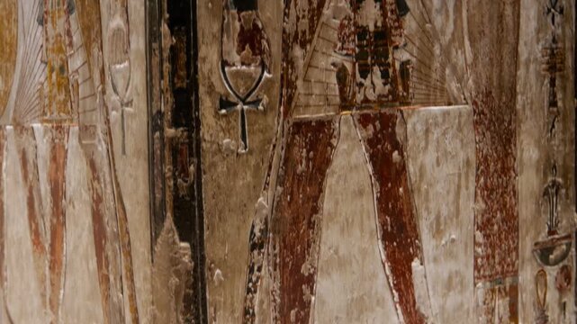 Close-up of ancient Egyptian relief carving inside KV17 tomb of Seti I, Valley of the Kings, Luxor, Egypt, showing a deity figure with black hair and deteriorating pigment.