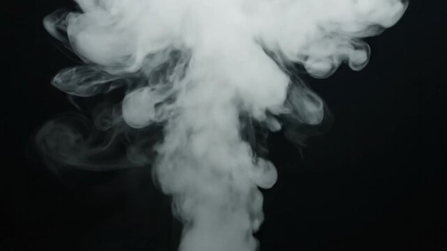 A thick cloud of white smoke rises against a dark background